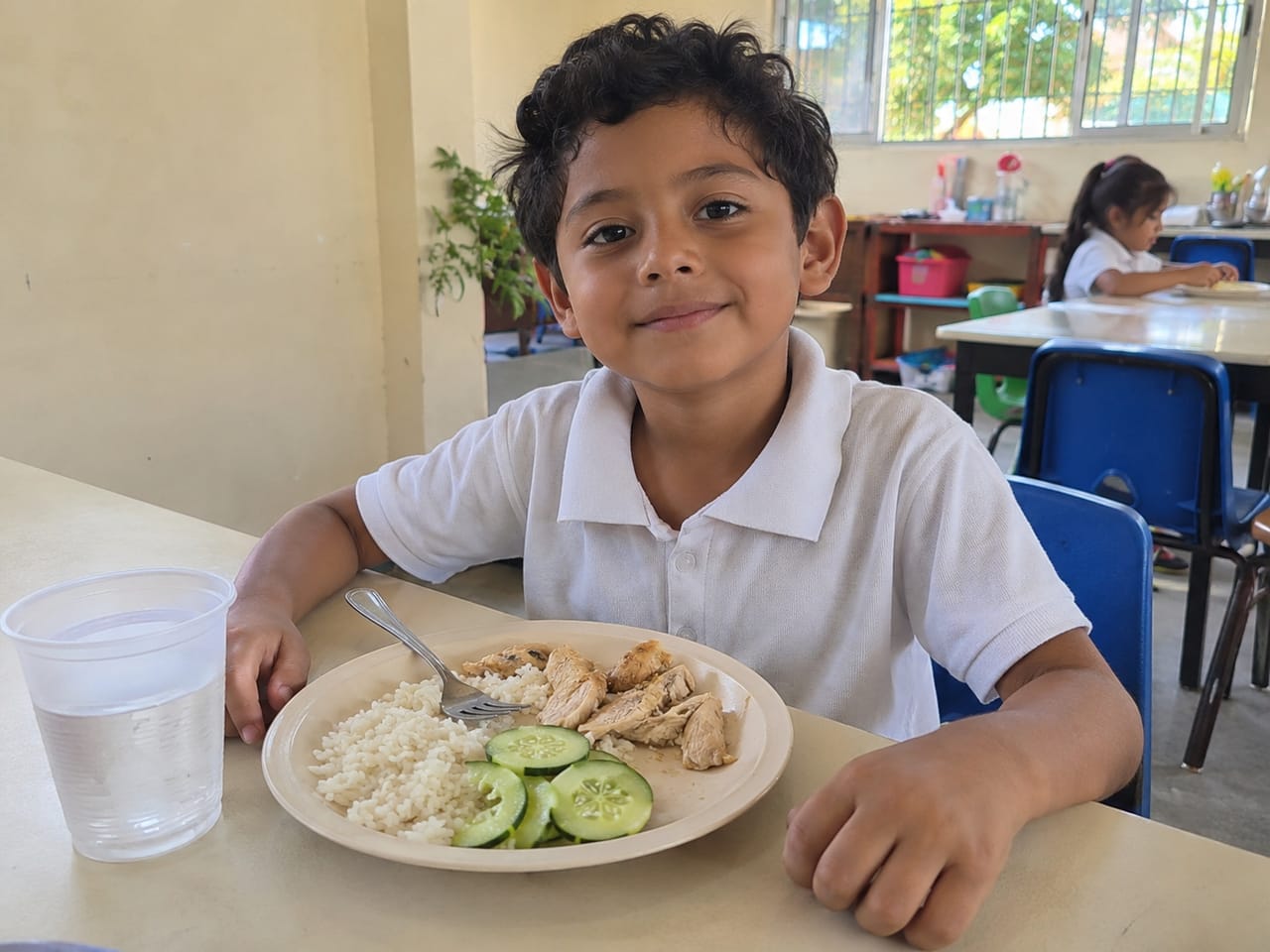 Niñas y niños comen juntos en el comedor del colegio